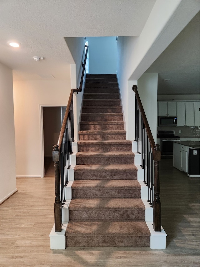 staircase with hardwood / wood-style flooring and a textured ceiling