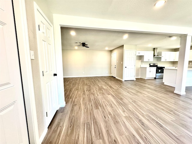 unfurnished living room featuring light hardwood / wood-style floors, a textured ceiling, and ceiling fan