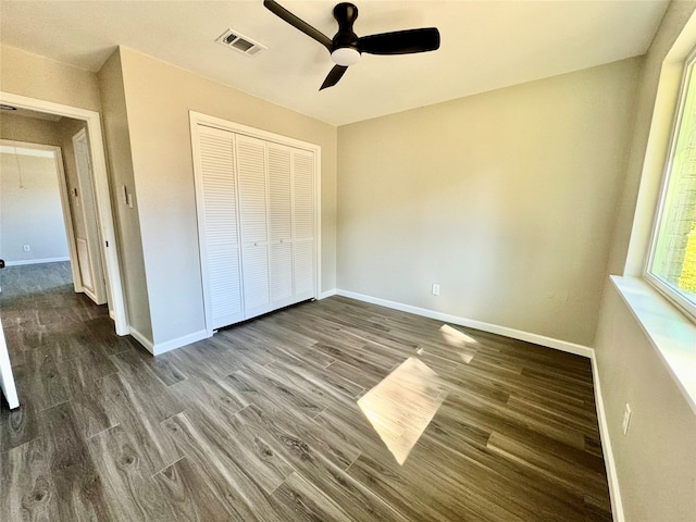 unfurnished bedroom with a closet, dark wood-type flooring, and ceiling fan