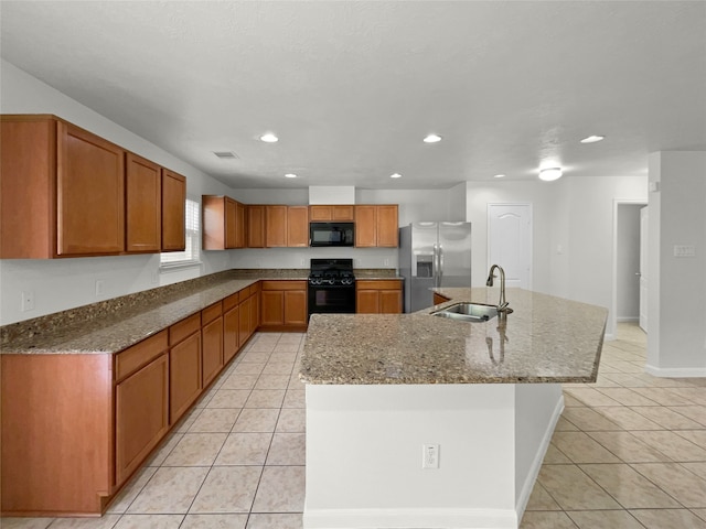 kitchen featuring a center island with sink, black appliances, sink, and light tile patterned floors