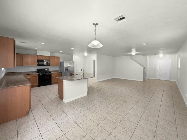 kitchen featuring a kitchen island with sink, dark stone countertops, sink, black appliances, and pendant lighting