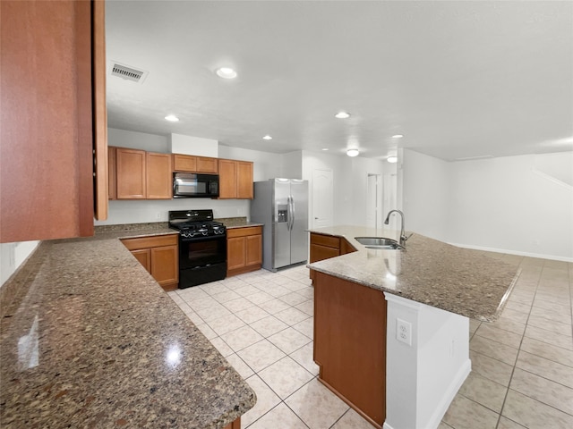 kitchen featuring a kitchen island with sink, a kitchen bar, black appliances, stone countertops, and sink