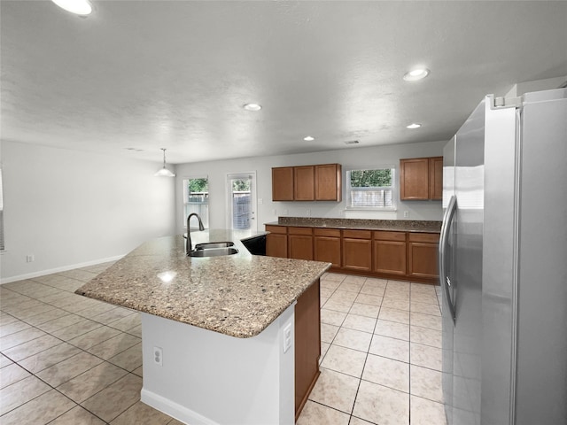 kitchen with a wealth of natural light, sink, stainless steel fridge, and a center island with sink