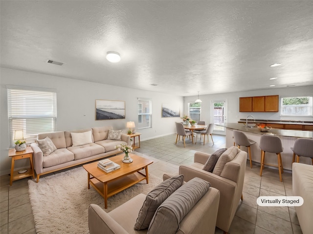 tiled living room with a textured ceiling and sink