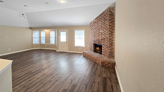 unfurnished living room featuring dark hardwood / wood-style flooring, a textured ceiling, and vaulted ceiling