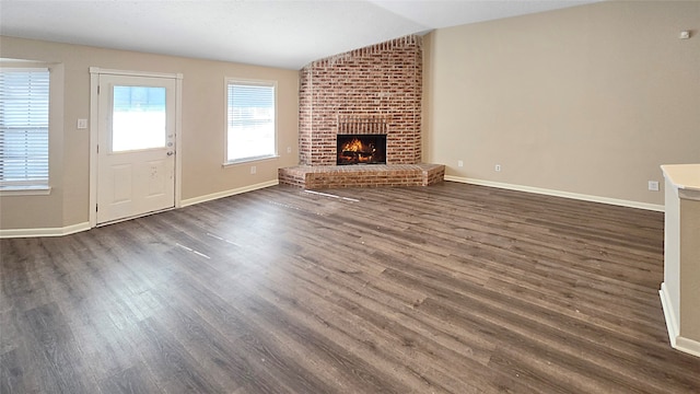 unfurnished living room with vaulted ceiling, dark hardwood / wood-style flooring, and a brick fireplace