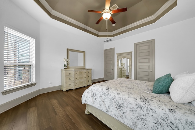 bedroom with ceiling fan, a tray ceiling, ornamental molding, and dark hardwood / wood-style flooring