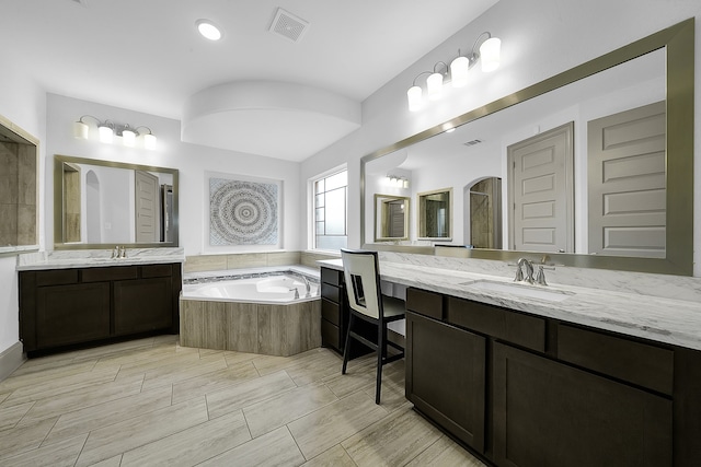 bathroom featuring vanity and tiled tub