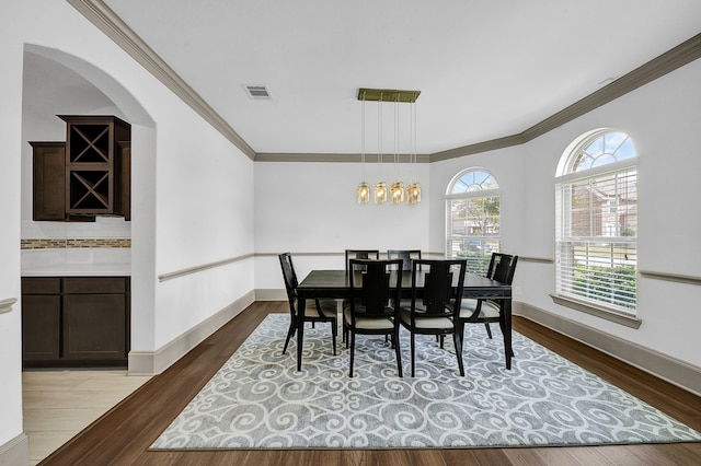 dining area featuring an inviting chandelier, hardwood / wood-style floors, and crown molding