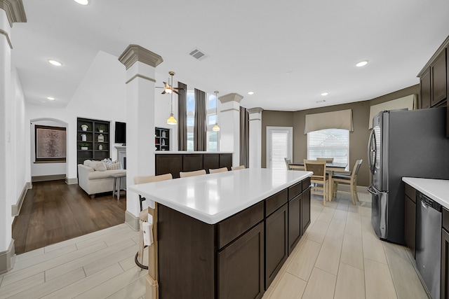 kitchen featuring a breakfast bar area, appliances with stainless steel finishes, ceiling fan, a kitchen island, and light hardwood / wood-style floors