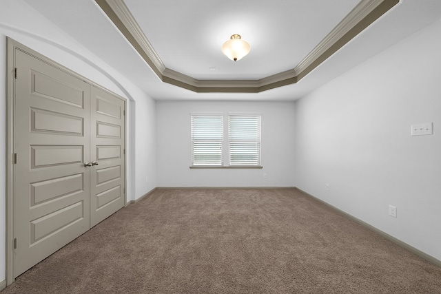 carpeted spare room featuring crown molding and a tray ceiling