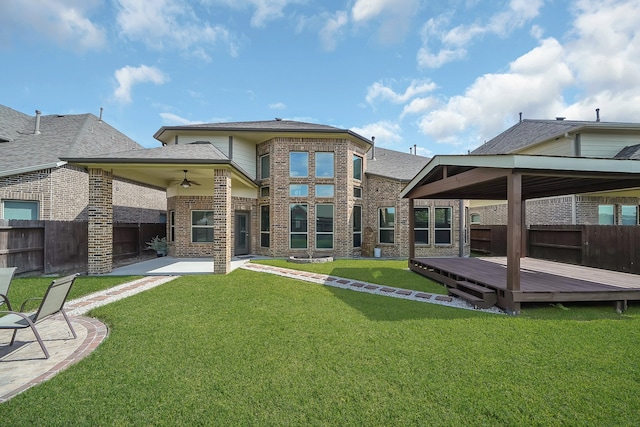 rear view of house featuring a wooden deck, a lawn, and ceiling fan