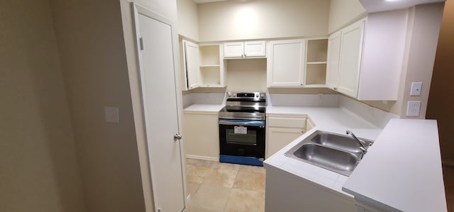 kitchen featuring stainless steel electric range, sink, and white cabinets