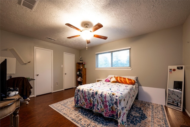 bedroom with ceiling fan, dark hardwood / wood-style flooring, and a textured ceiling