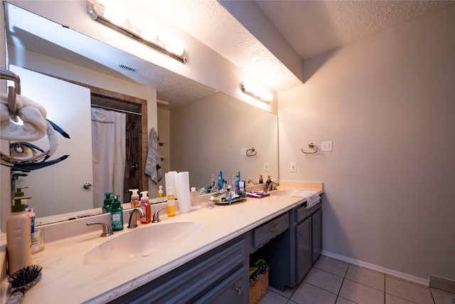 bathroom featuring tile patterned flooring, vanity, a textured ceiling, and walk in shower