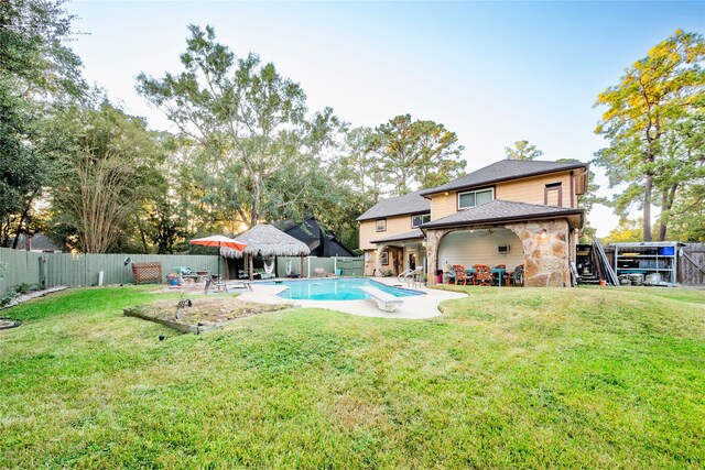 rear view of house with a gazebo, a yard, a fenced in pool, and a patio area