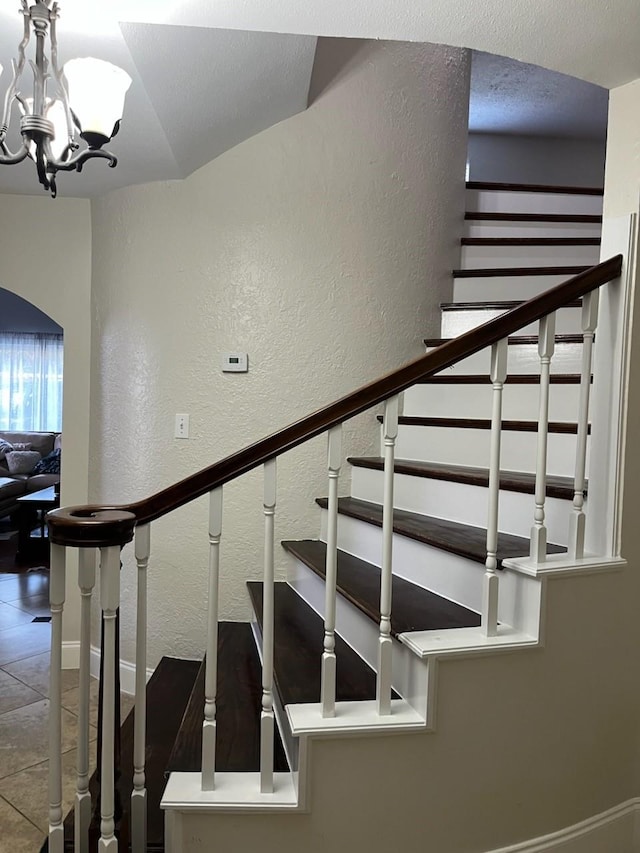 staircase featuring tile patterned flooring and an inviting chandelier