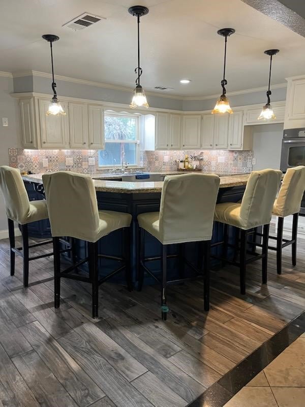 kitchen with a kitchen bar, decorative light fixtures, and light stone countertops