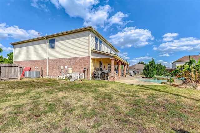 back of property with a yard, central AC, and a patio area