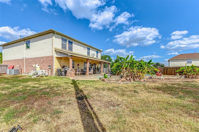 back of house featuring central AC, a patio, and a lawn