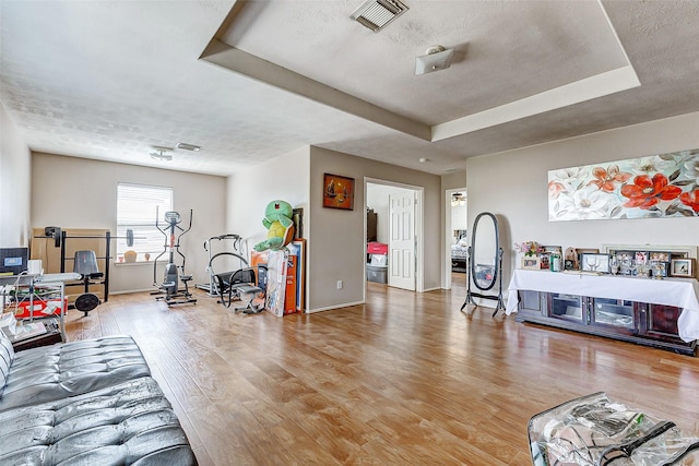 living room featuring wood-type flooring and a tray ceiling