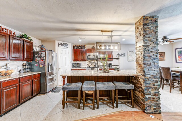 kitchen with tasteful backsplash, a kitchen bar, decorative light fixtures, and appliances with stainless steel finishes