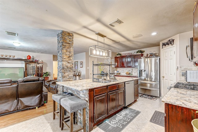 kitchen with sink, ornate columns, hanging light fixtures, stainless steel appliances, and backsplash