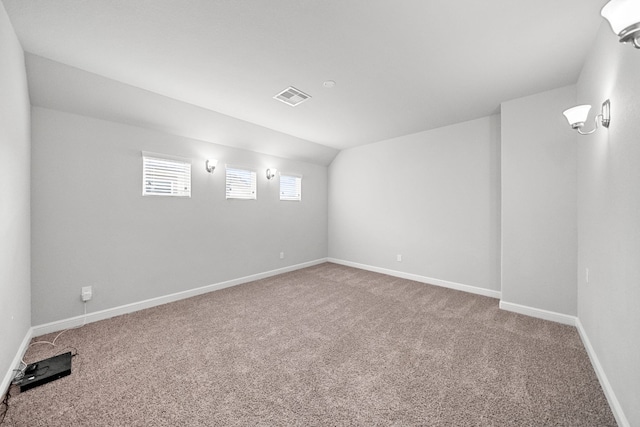 carpeted empty room featuring vaulted ceiling