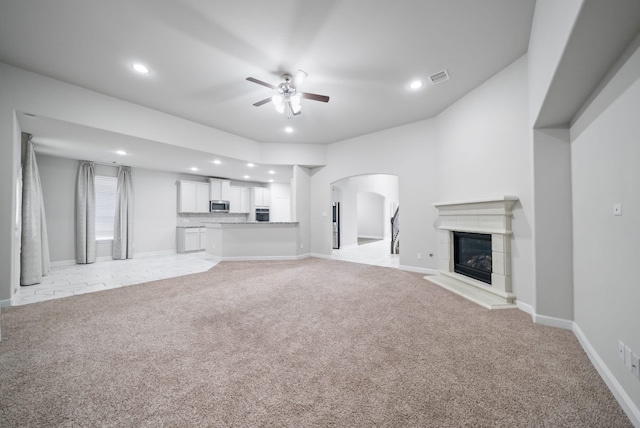 unfurnished living room with light colored carpet and ceiling fan