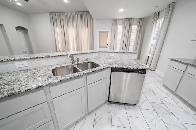 kitchen with sink, light stone countertops, stainless steel dishwasher, white cabinetry, and ceiling fan