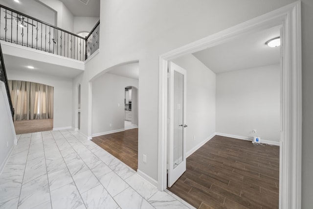 hallway featuring a towering ceiling and hardwood / wood-style floors