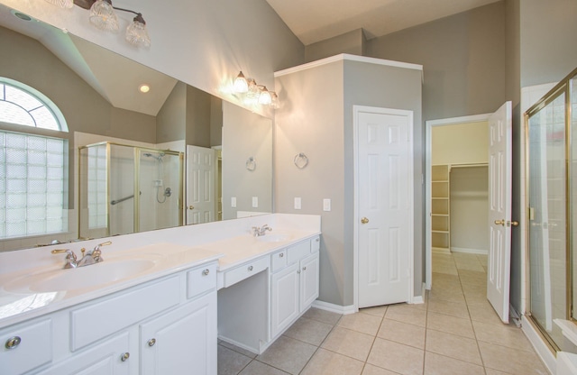 bathroom featuring a shower with door, lofted ceiling, vanity, and tile patterned flooring