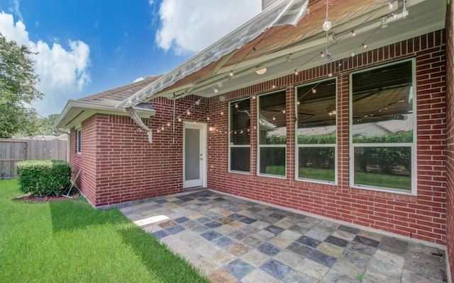 exterior space with brick siding, fence, and a patio