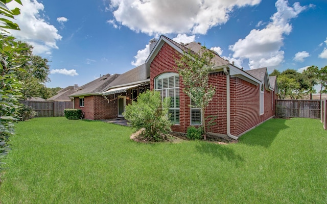 rear view of property with brick siding, a lawn, and a fenced backyard