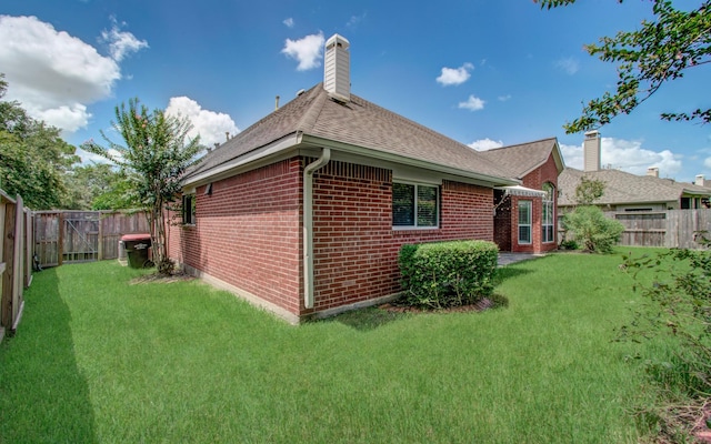 back of property with a lawn, a fenced backyard, a chimney, and brick siding