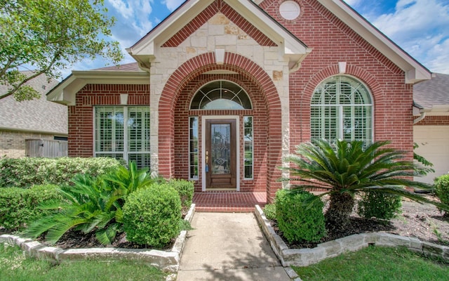 view of exterior entry featuring brick siding, an attached garage, and stone siding