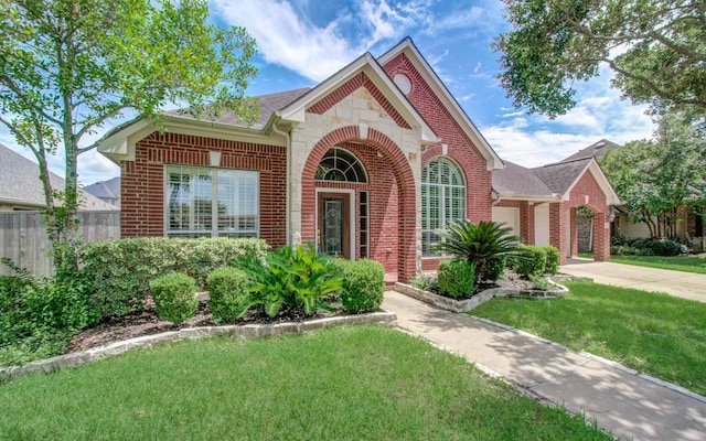 view of front of house featuring brick siding, a garage, concrete driveway, a front yard, and roof with shingles