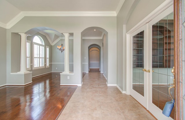 foyer with french doors, arched walkways, baseboards, wood finished floors, and ornamental molding
