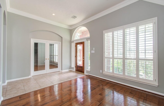 foyer entrance with wood finished floors, visible vents, ornamental molding, french doors, and baseboards