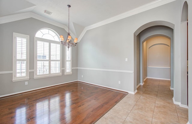 empty room featuring vaulted ceiling, a chandelier, visible vents, and plenty of natural light
