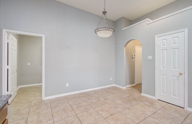 tiled spare room with a towering ceiling