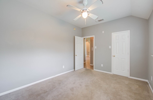 unfurnished bedroom featuring light colored carpet, vaulted ceiling, and ceiling fan