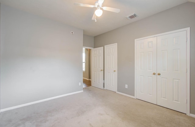 unfurnished bedroom with carpet, visible vents, baseboards, and multiple closets