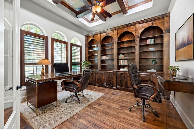 office space featuring beamed ceiling, coffered ceiling, light wood-type flooring, and ceiling fan