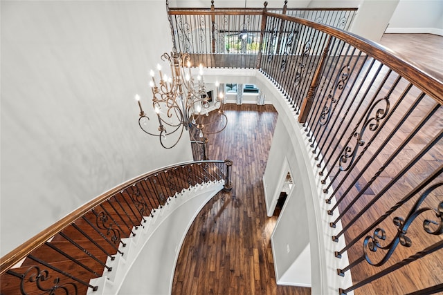 stairs with a notable chandelier and hardwood / wood-style flooring