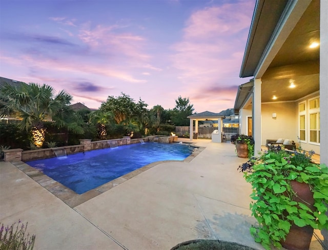 pool at dusk with a patio and pool water feature