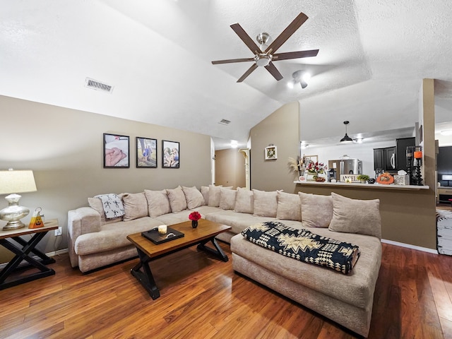 living room featuring ceiling fan, a textured ceiling, lofted ceiling, and hardwood / wood-style floors