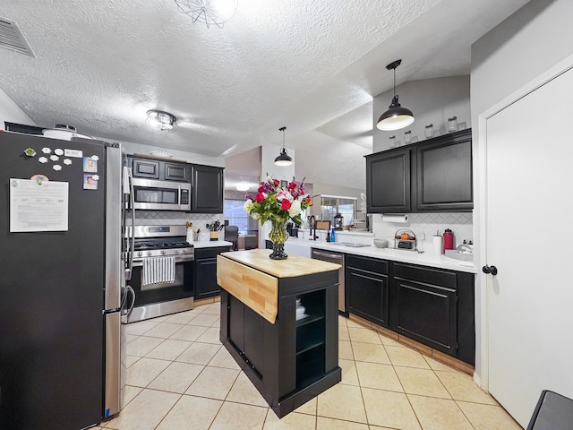 kitchen with vaulted ceiling, decorative light fixtures, stainless steel appliances, and tasteful backsplash