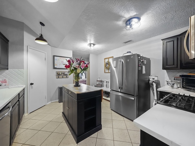 kitchen featuring stainless steel appliances, a center island, pendant lighting, a textured ceiling, and tasteful backsplash