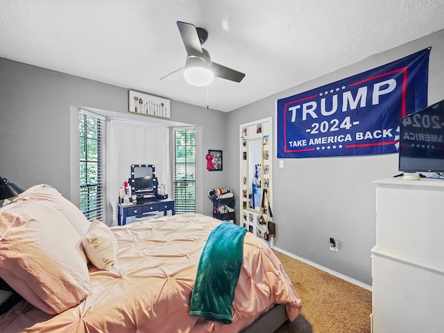 bedroom with a textured ceiling, carpet flooring, and ceiling fan